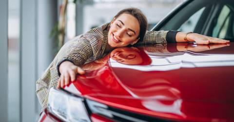 vrouw omarmt haar rode auto liefdevol