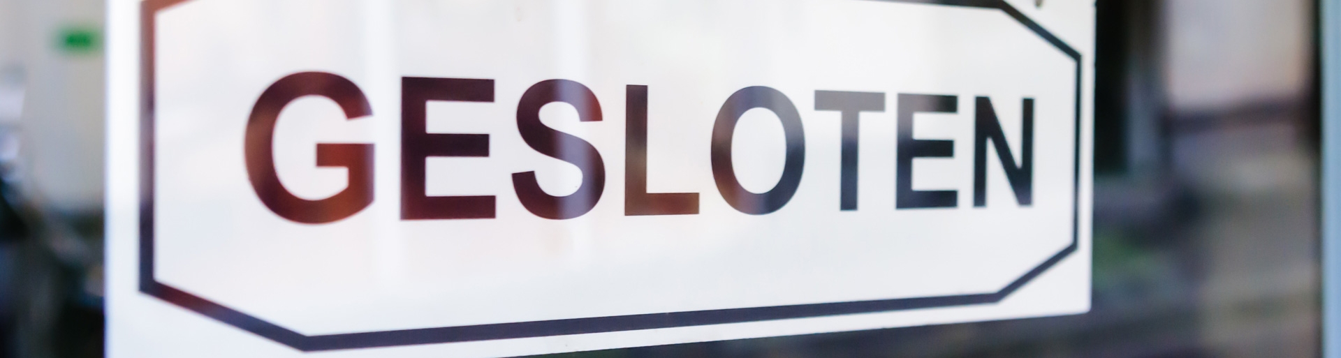 Een bordje op een raam met de tekst 'Gesloten'